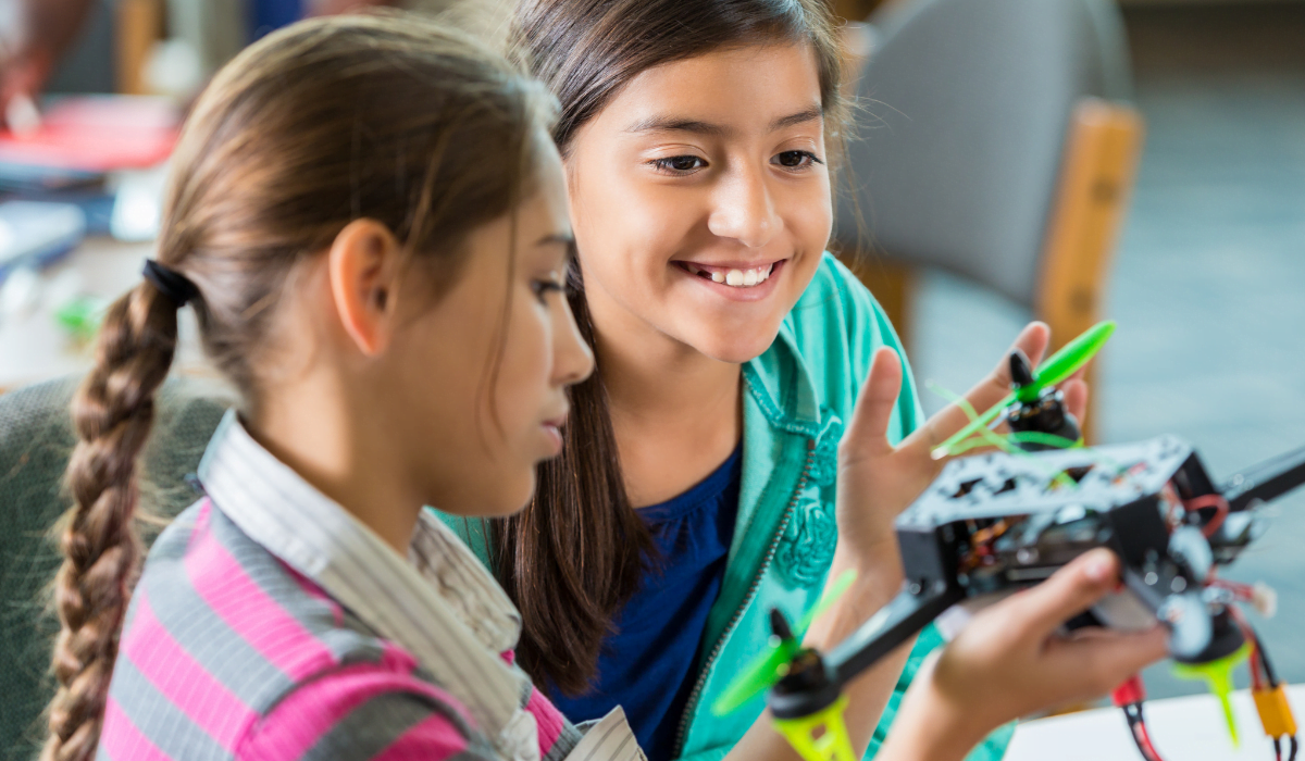 Two girls study a drone