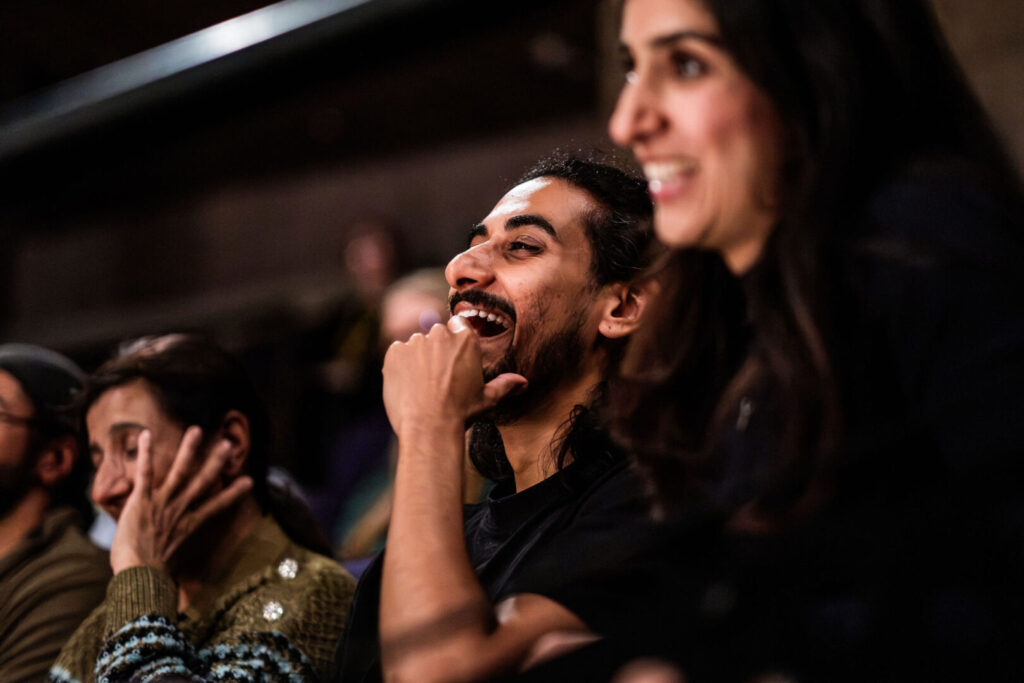 We are close in to some members of an audience who are all laughing.