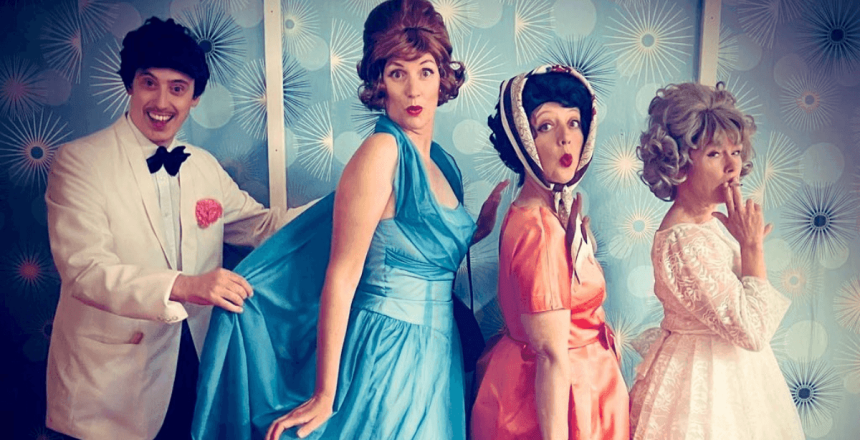 Three people dressed in 50s costume are standing in a row pointing towards the right-hand side but facing the viewer. Three women at the front of the line wear pastel-coloured dresses. The one at the front in white smokes a cigarette; the middle lady in orange has a patterned headscarf tied under her chin and holds a white board with ‘Twist Contest’ written in black; and the woman at the back in a long blue gown has a surprised look on her face. Behind her a man in white tux, black bowtie and trousers, with a pink pocket square, is holding the drape of her dress. They stand in front of a wall of blue wallpaper with a 50s-inspired pattern of white circles and sunbursts.